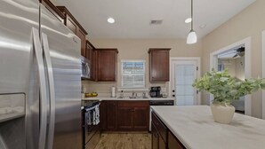 Una cocina con gabinetes de madera, un refrigerador de acero inoxidable, un lavamanos y una planta en maceta.