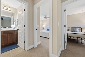 Een hotelkamer met badkamer, een slaapkamer met bed en nachtkastje, en een apart slaapgedeelte met bed.