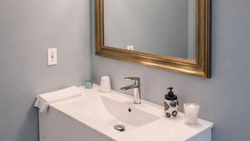 A bathroom with a white vanity, a gold-framed mirror, and a light blue wall.