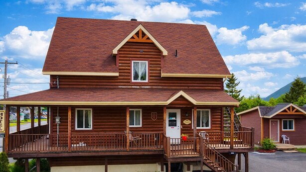 A two-story log cabin with a porch, a small staircase, and a sign indicating it is a motel. - Motel Au Vieux Frontenac (Thetford Mines)