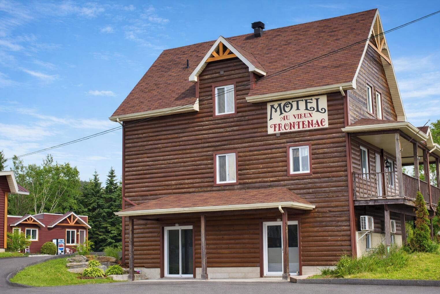 A two-story log cabin with a sign reading "Motel au Vieux Frontenac."
