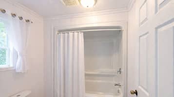 A bathroom with a toilet, a bathtub, and a shower curtain.