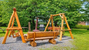 A wooden swing set in a park with a picnic table and grill in the background. - Motel Au Vieux Frontenac (Thetford Mines)