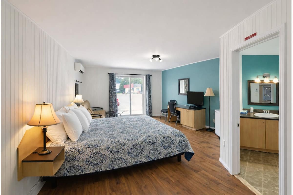 A hotel room with a bed, desk, and bathroom.