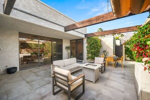 Een modern terras buiten met een bank, stoelen en een tafel.