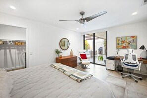 Een moderne slaapkamer met een bed, een bureau, een stoel, een kledingkast en een plafondventilator.