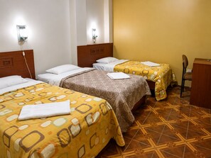 A hotel room with two beds, each with a patterned bedspread, a wooden headboard, and a nightstand with a lamp. - Hotel Tamaris Chiclayo (Chiclayo)