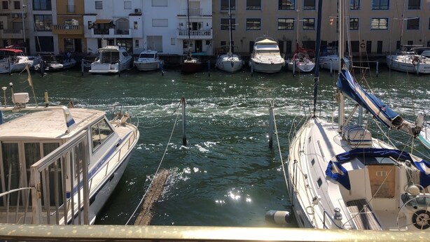 Un port de plaisance où sont amarrés plusieurs bateaux, entouré d’immeubles à étages dotés de balcons.