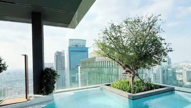 Una piscina a sfioro sulla terrazza con vista sulla città, circondata da vegetazione e architettura moderna.