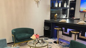 A modern bar area with two green upholstered chairs, a glass coffee table, and a bar counter with stools. - Beautiful, New,Clean,Luxurious Guest House in Great, safe location near consulate (Juárez)