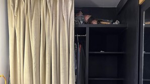 A room with a black wardrobe, a beige curtain, and a small table with a towel and a bottle. - Beautiful, New,Clean,Luxurious Guest House in Great, safe location near consulate (Juárez)