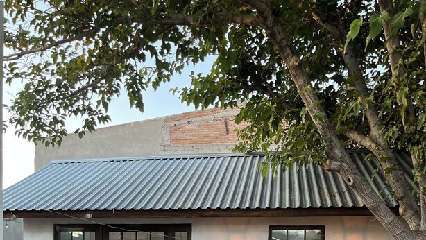 A building with a corrugated metal roof, large glass doors, and two wall-mounted lights. - Beautiful, New,Clean,Luxurious Guest House in Great, safe location near consulate (Juárez)