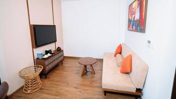 Una sala de estar moderna con un sofá, un televisor, un armario de madera y una silla de mimbre.