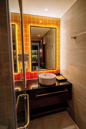 Een moderne badkamer met een grote spiegel, een rond wastafeltje en een haardroger.