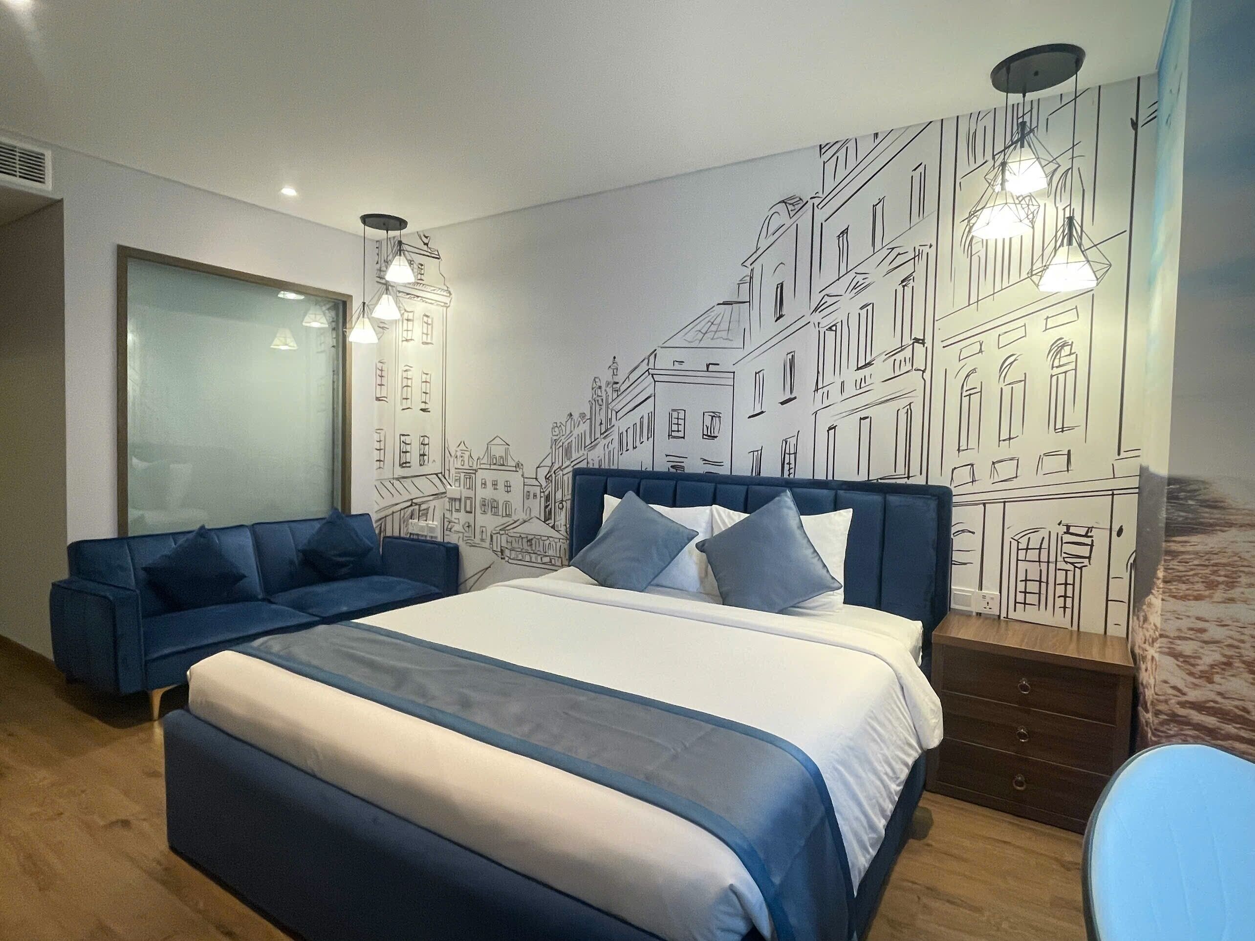 Ein modernes Schlafzimmer mit einem großen Bett, einem blauen Sofa und einem Stadtbild-Wandgemälde.