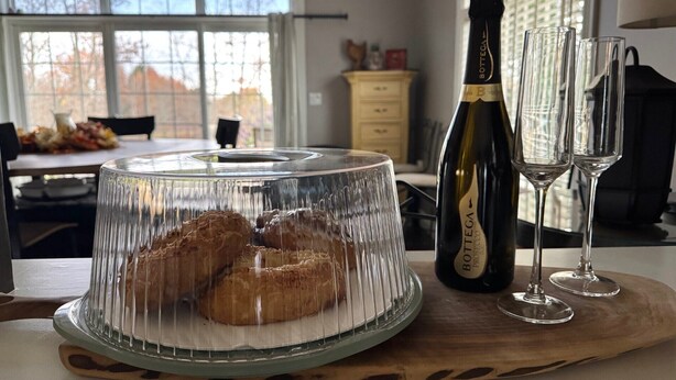 Ein Esstisch mit einer Kuchenplatte, einer Weinflasche und zwei Gläsern auf einer Holzbrett.