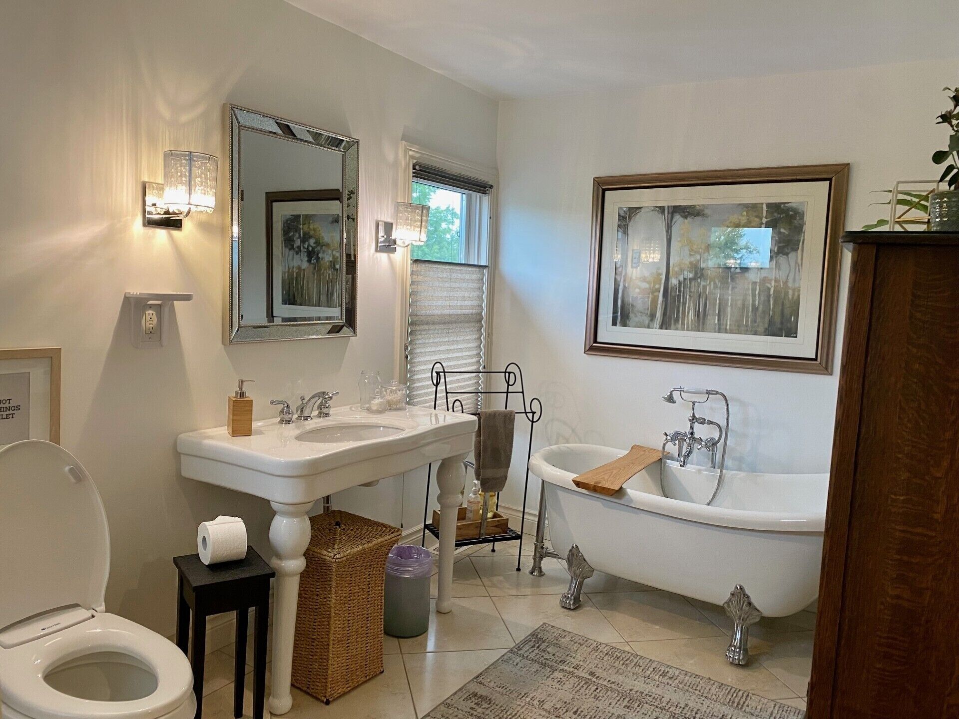 A bathroom with a toilet, two sinks, a bathtub, a mirror, and a framed picture on the wall.