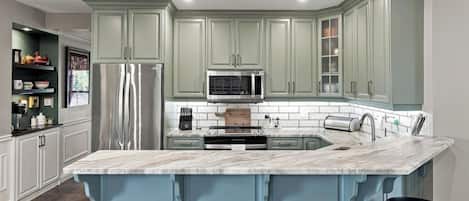 A kitchen with a central island, stainless steel appliances, and light-colored cabinetry.