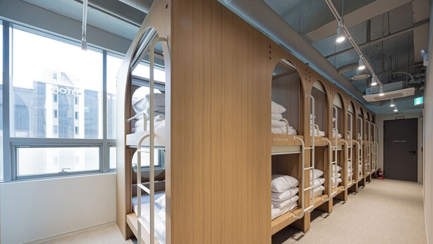 A hotel room with bunk beds, a large window, and a view of the city. - Haeundae Marine Capsule Hotel & Spa (Busan)