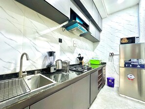 A modern kitchen with a stainless steel refrigerator, a built-in gas stove, and a sink with a dish rack. - 2-bedroom Apartment in serene Opic Estate with AC comfort (Opic)
