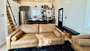 A modern kitchen with a central island, stainless steel appliances, and a wooden ceiling.