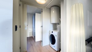 A laundry room with a washing machine, a ceiling light, and a curtain. - El Niu del Pirineu (Err)
