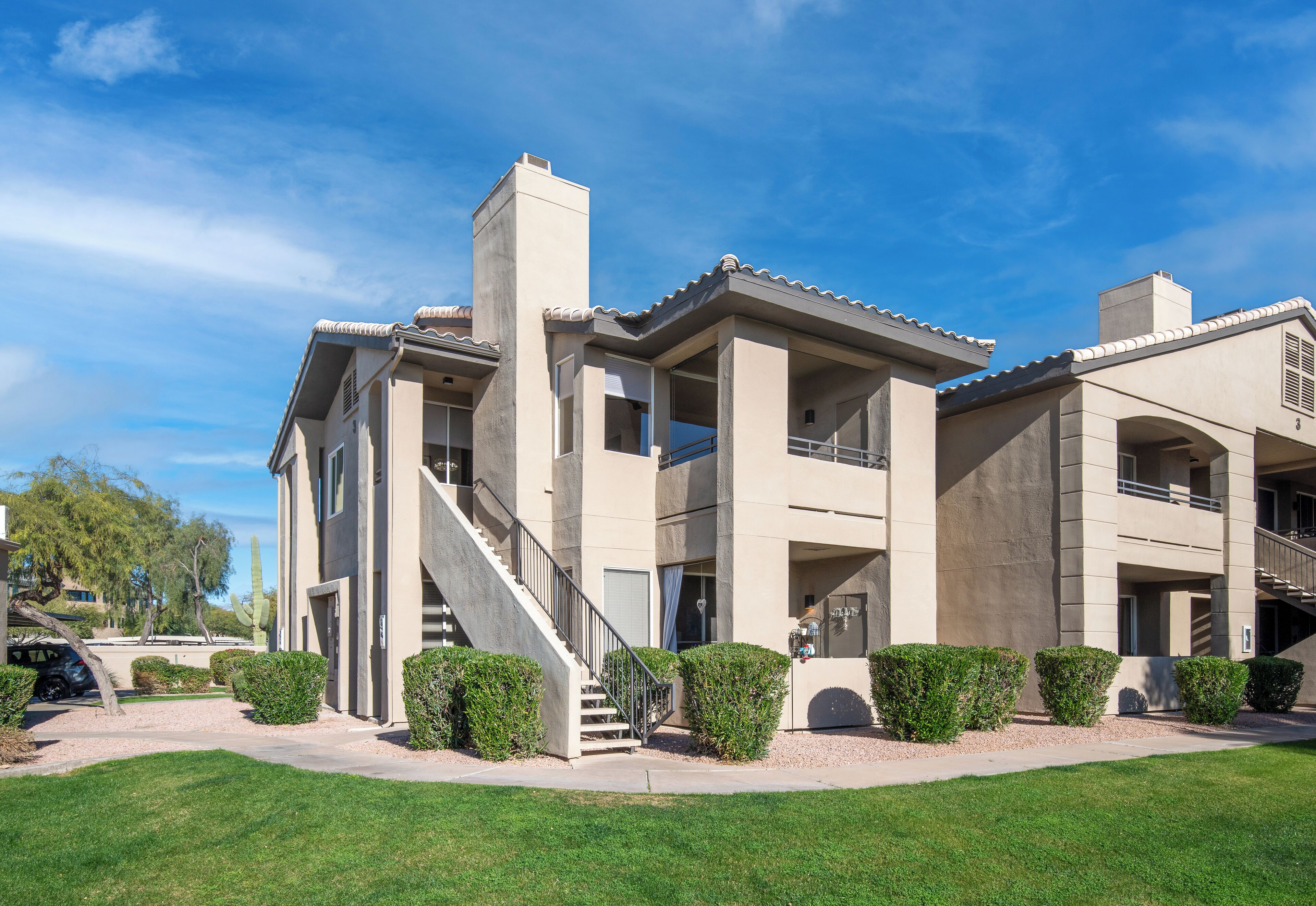 A modern multi-story building with a central staircase, balconies, and a covered outdoor area.