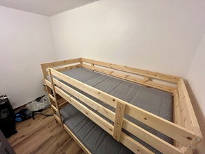 A bunk bed with grey bedding in a room with wooden flooring and white walls.