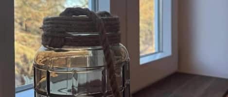 A clear glass lantern with a candle inside, placed on a window sill.