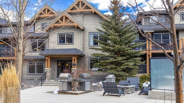A two-story building with a stone foundation, a covered porch, and outdoor seating with a grill. - Contemporary 2BR w/ hot tub and Mountain Views (Dead Man`s Flats)