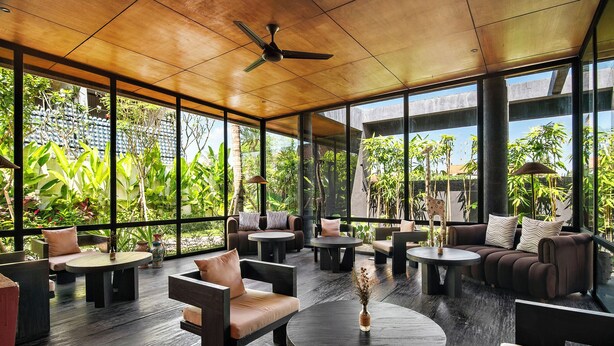 A spacious indoor area with multiple seating arrangements, large windows, and a ceiling fan. - The Craft Hotel Ubud (Ubud)