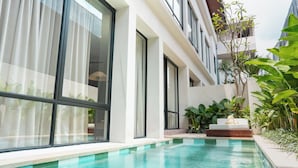 A modern hotel with a swimming pool, large windows, and lush greenery. - The Craft Hotel Ubud (Ubud)