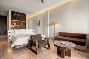 A modern hotel room with a bed, a sofa, a chair, and a small table. - The Craft Hotel Ubud (Ubud)