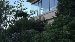 Un bâtiment moderne doté de grandes fenêtres, entouré d’une végétation luxuriante et de plantes en fleurs.