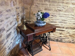 Une machine à coudre ancienne, avec un plateau en bois, une lampe en laiton et un vase rempli de fleurs.