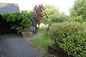 A garden with a gravel path, stone walls, and various shrubs and trees.