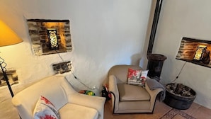 Ein gemütliches Wohnzimmer mit einer Couch, einem Sessel, einem Kamin und dekorativer Wandkunst.
