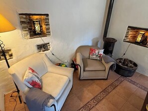 A cozy living room with a sofa and armchair, a fireplace, and decorative wall art.