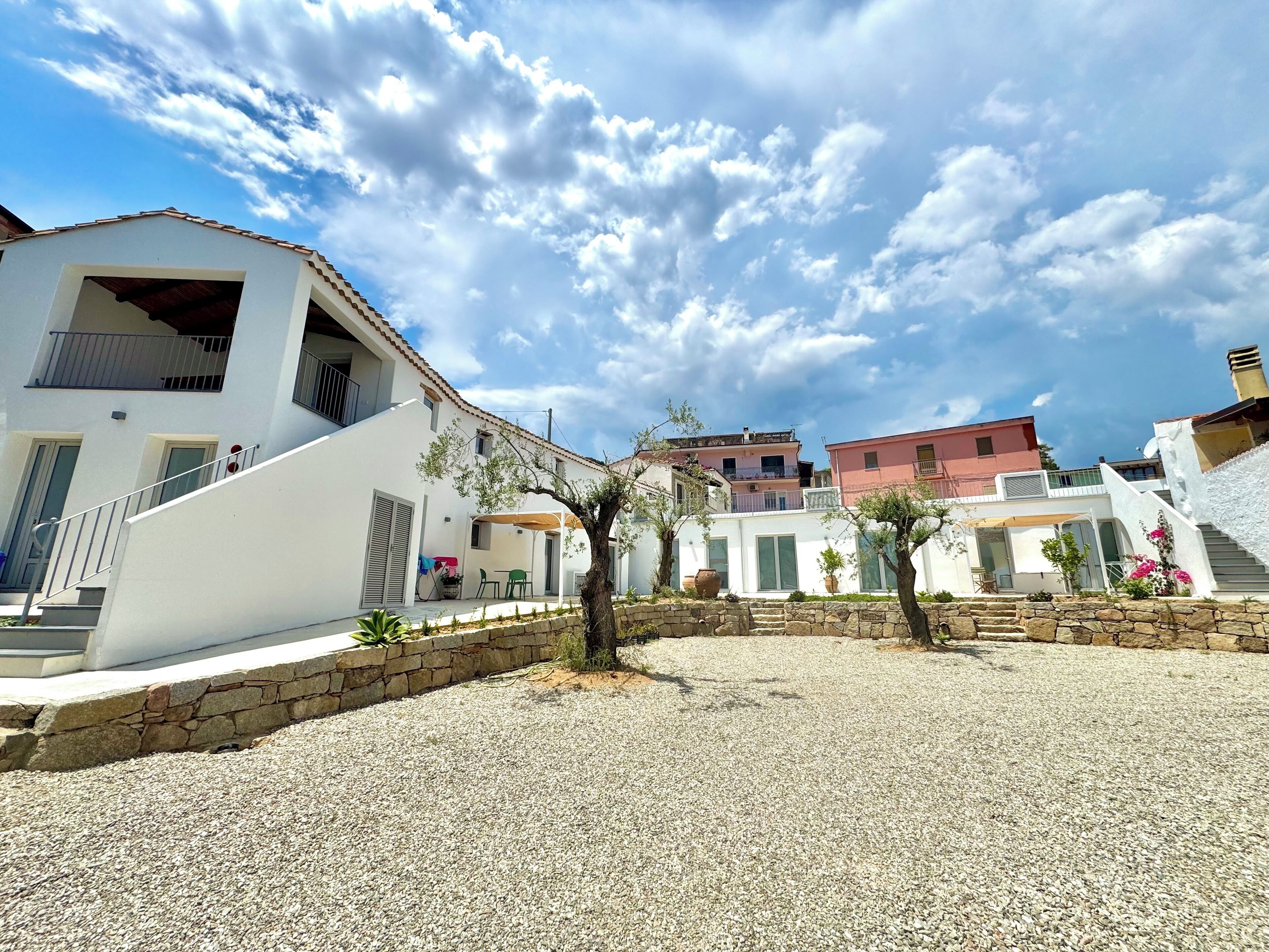 Zona residencial con edificios blancos, un patio de grava y cielo despejado.