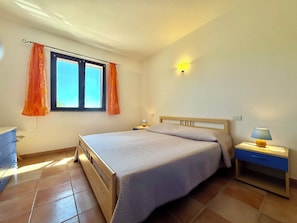A bedroom with a bed, a nightstand, a lamp, a window with curtains, and a dresser. - " Blue Design Apartment " (Tortolì)