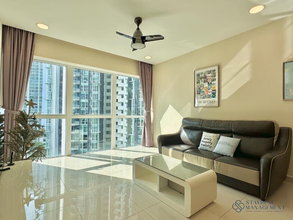 A modern living room with a glass coffee table, a leather sofa, and a ceiling fan.