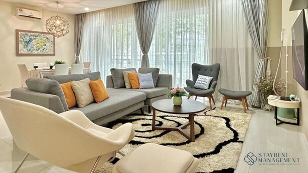 Ein modernes Wohnzimmer mit grauem Sofa, weißen Sesseln, einem Couchtisch und einem Fernseher.