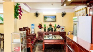 A room with a wooden reception desk, a glass display case, a water dispenser, a painting on the wall, and a refrigerator. - Minh Duc 2 Hotel (Trung Khanh)