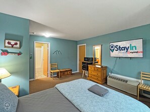 Una camera da letto con un letto, una cassettiera, una sedia e un cartello appeso al muro.