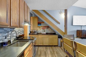 A kitchen with wooden cabinets, a black countertop, and a microwave.
