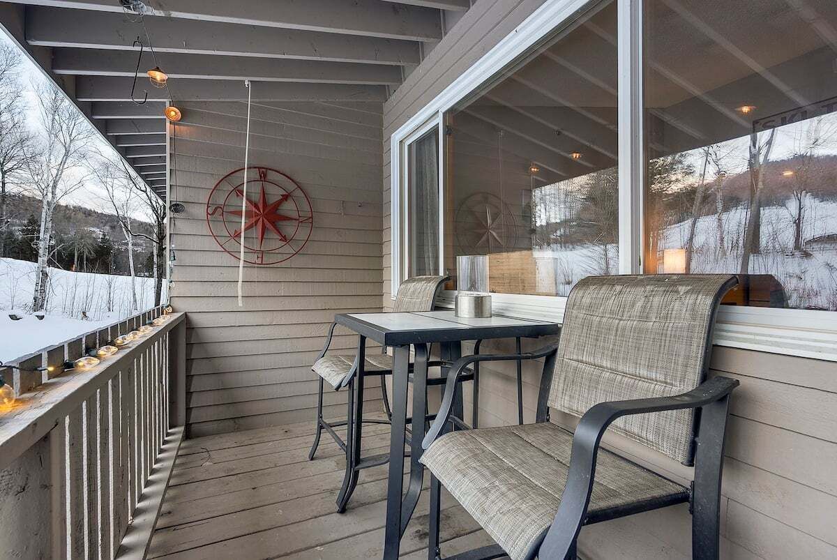 Une véranda abritée avec une table et des chaises, une décoration en forme de boussole et une vue sur un paysage enneigé.