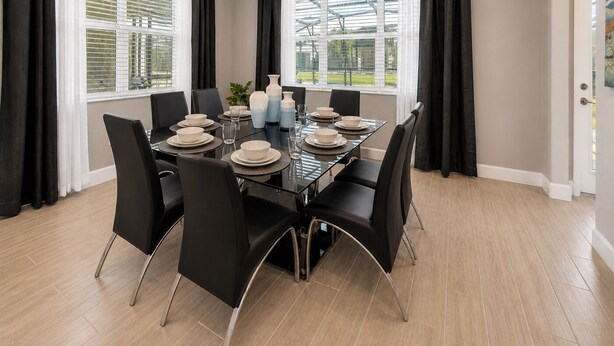 A dining area with a table set for six, black chairs, and a view through large windows.