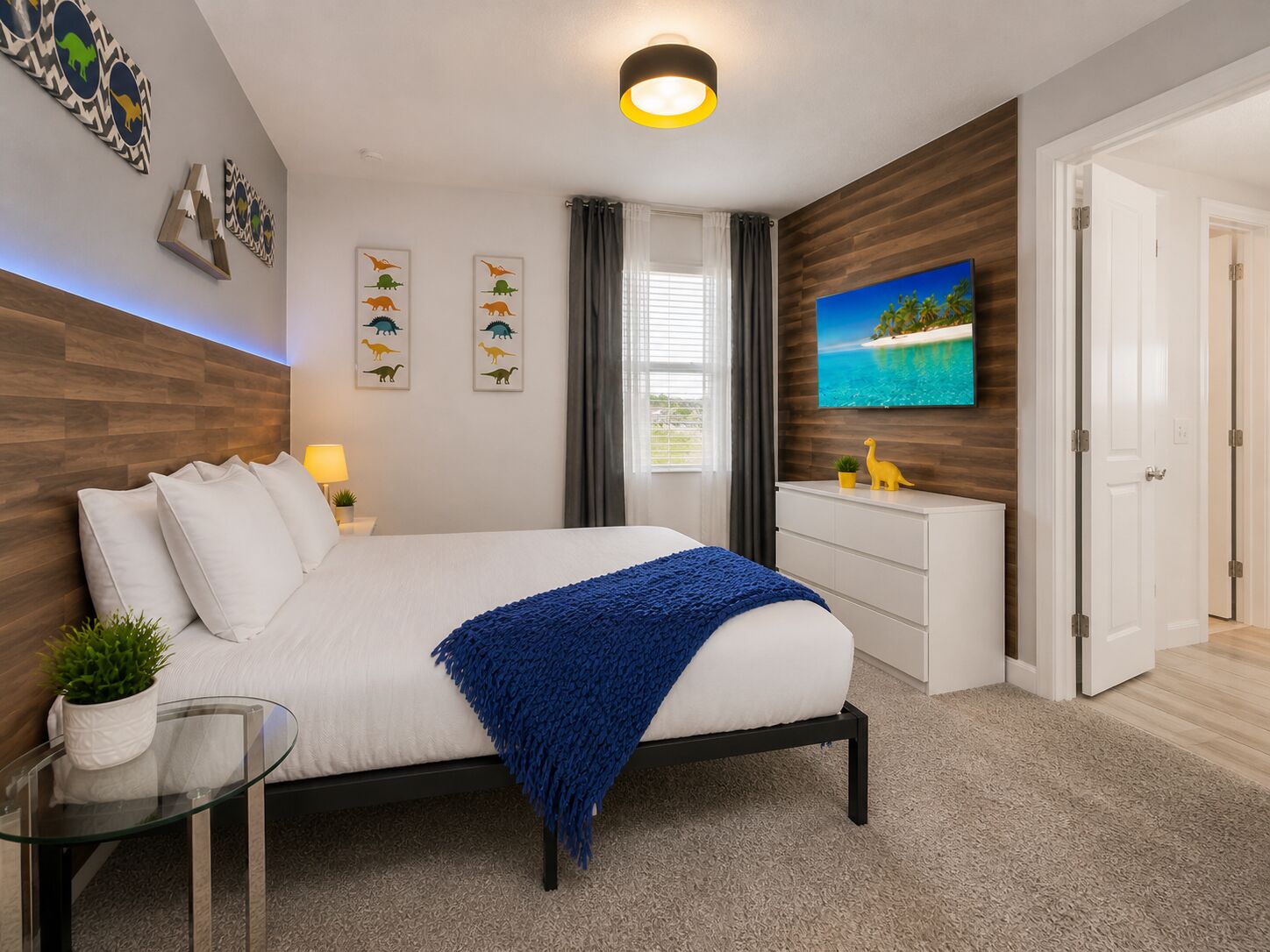 Ein modernes Schlafzimmer mit Bett, Fernseher, Schreibtisch und einer Tür.