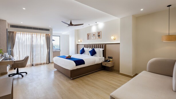A modern hotel room with a large bed, a desk, a chair, and a sofa. - Regenta Z Sunrise Gachibowli Hyderabad (Hyderabad)