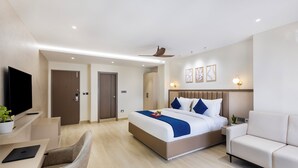 A modern hotel room with a large bed, a desk, a sofa, and a TV. - Regenta Z Sunrise Gachibowli Hyderabad (Hyderabad)
